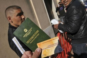 Un grupo de emigrantes muestra el permiso de residencia italiano